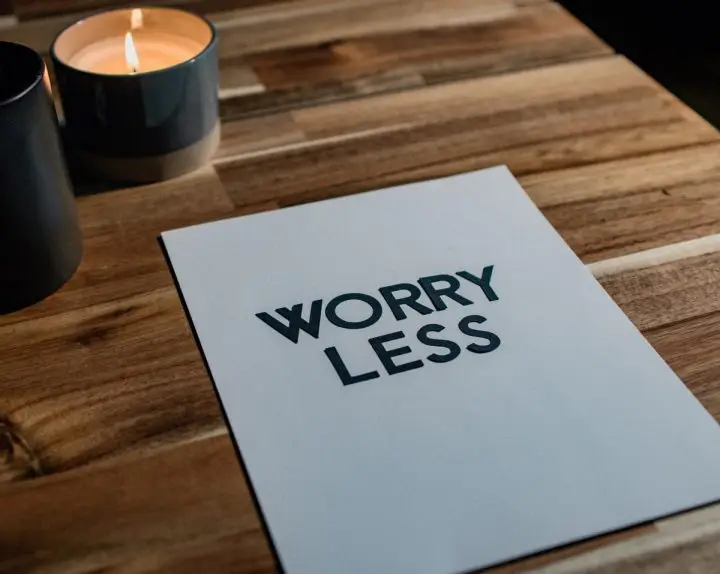 How to worry less about your financial situation by doing something about it.
Piece of white paper on a desk with candles that states Worry Less. 